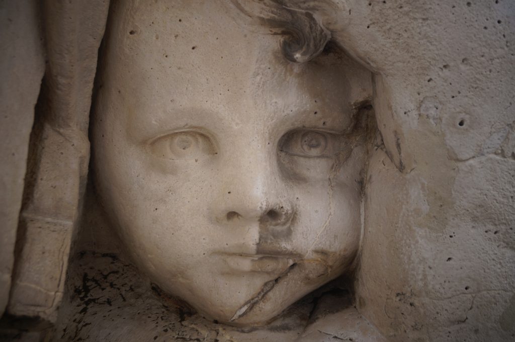 escultura de la cara de una niña con superficie envejecida