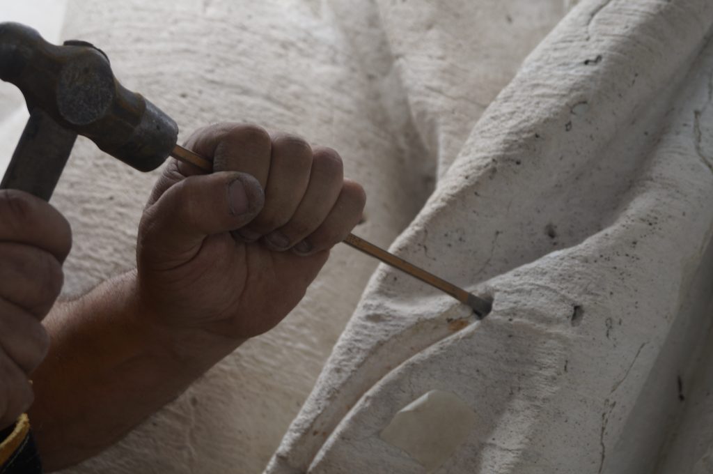 mano con martillo y clavo largo incrustado en escultura