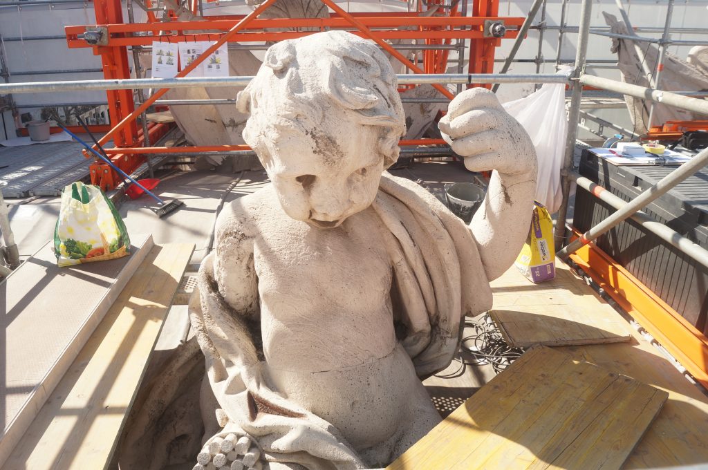 escultura blanca de niño antes de restaurar entre andamios