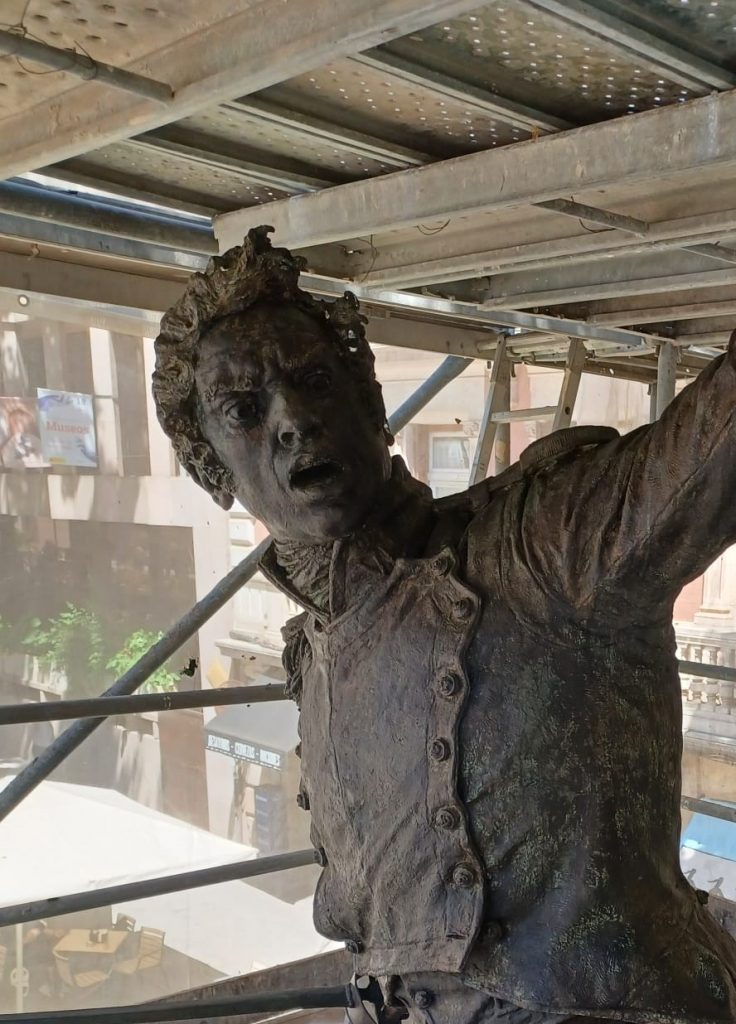 escultura en bronce de hombre entre andamios