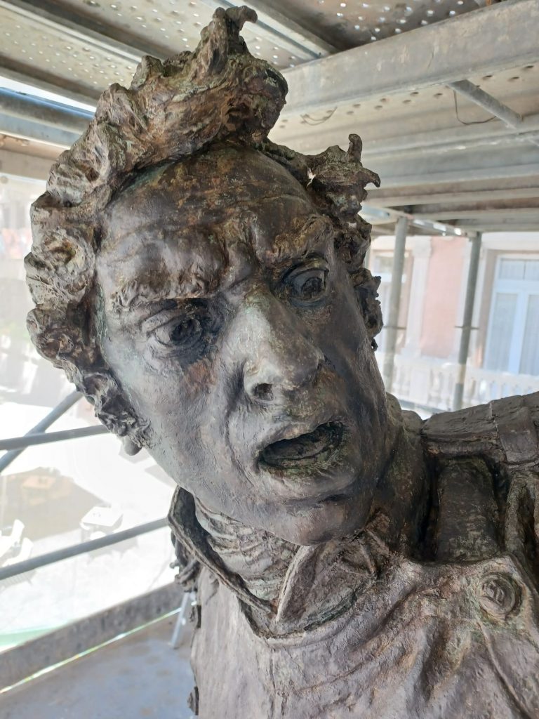 cara de escultura en bronce con boca abierta